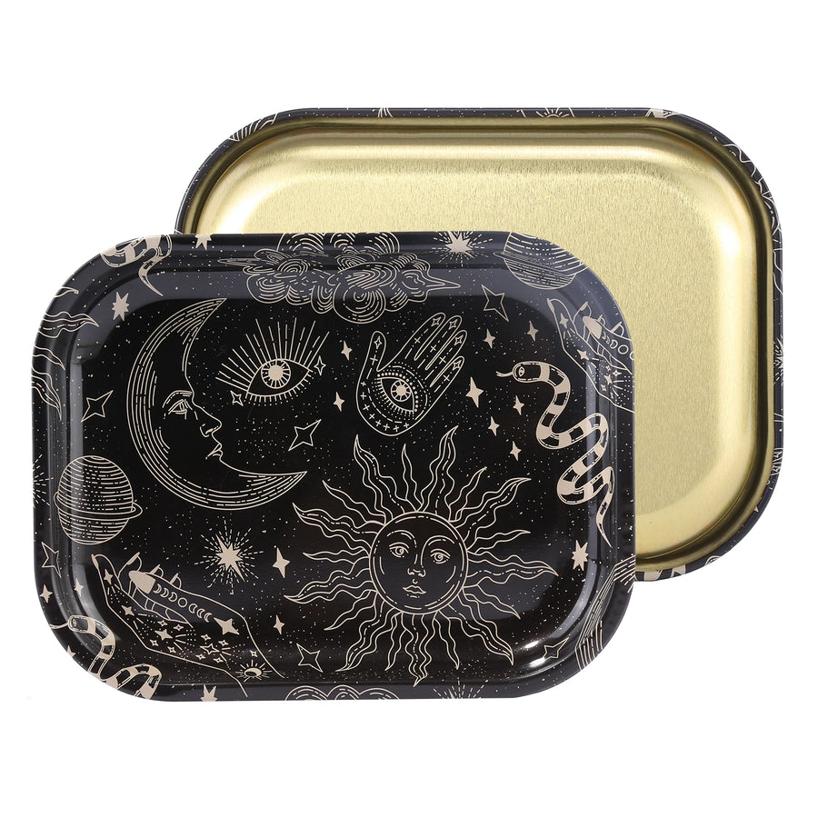 Two square metal rolling trays with rounded corners, one showing a black exterior decorated with gold celestial illustrations like a sun, moon, hand, and stars, and the other showing a gold interior.