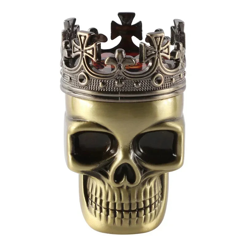 A skull-shaped container or decor piece with a metallic gold finish and a crown on top, photographed against a plain white background.