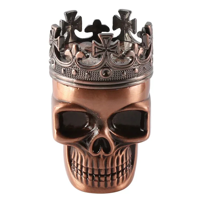 A skull-shaped decorative object topped with an ornate crown, finished in a metallic copper/bronze tone with dark recessed details, shown on a plain white background.
