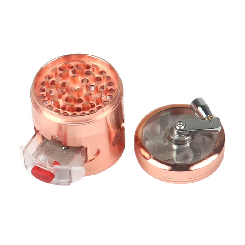A copper-colored metal herb grinder shown disassembled on a white background, with the main cylindrical body on the left and the lid on the right. The lid features a clear window and a silver metal crank handle.